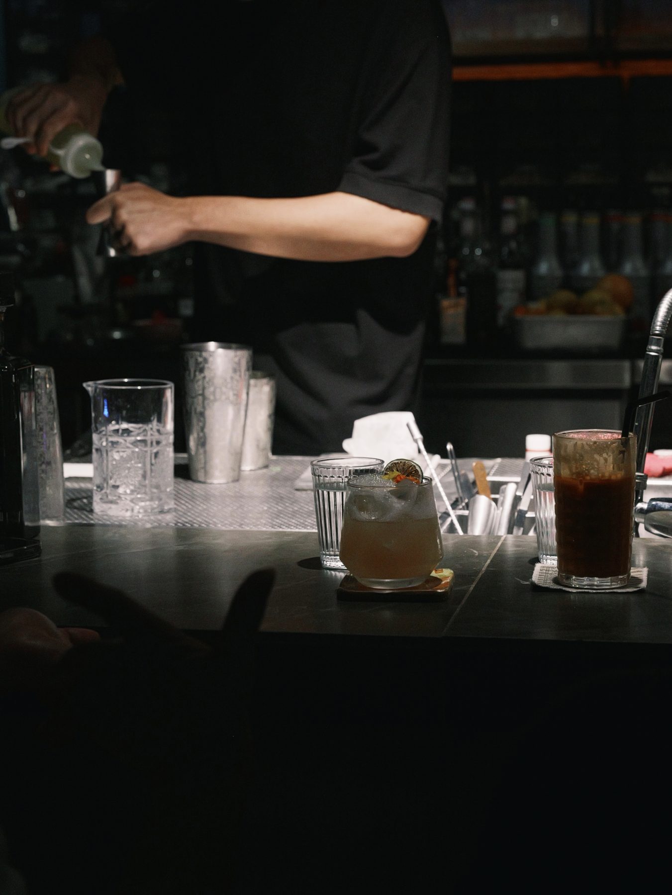 Bartender mixing custom cocktails behind the Dissolved Solids bar in low light