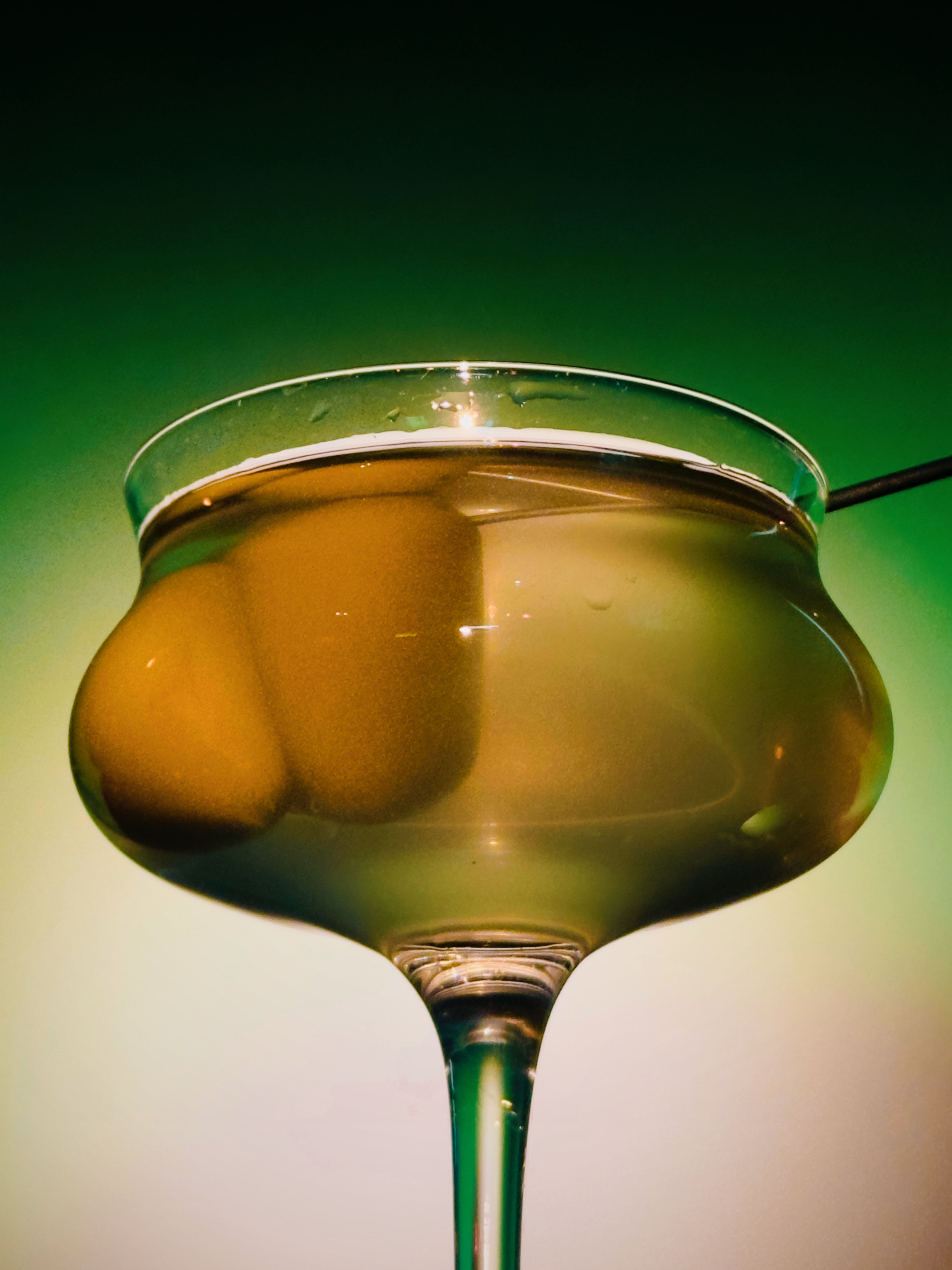 Stemmed coupe cocktail in amber-green tones against a soft gradient at Soluble Solids SS2