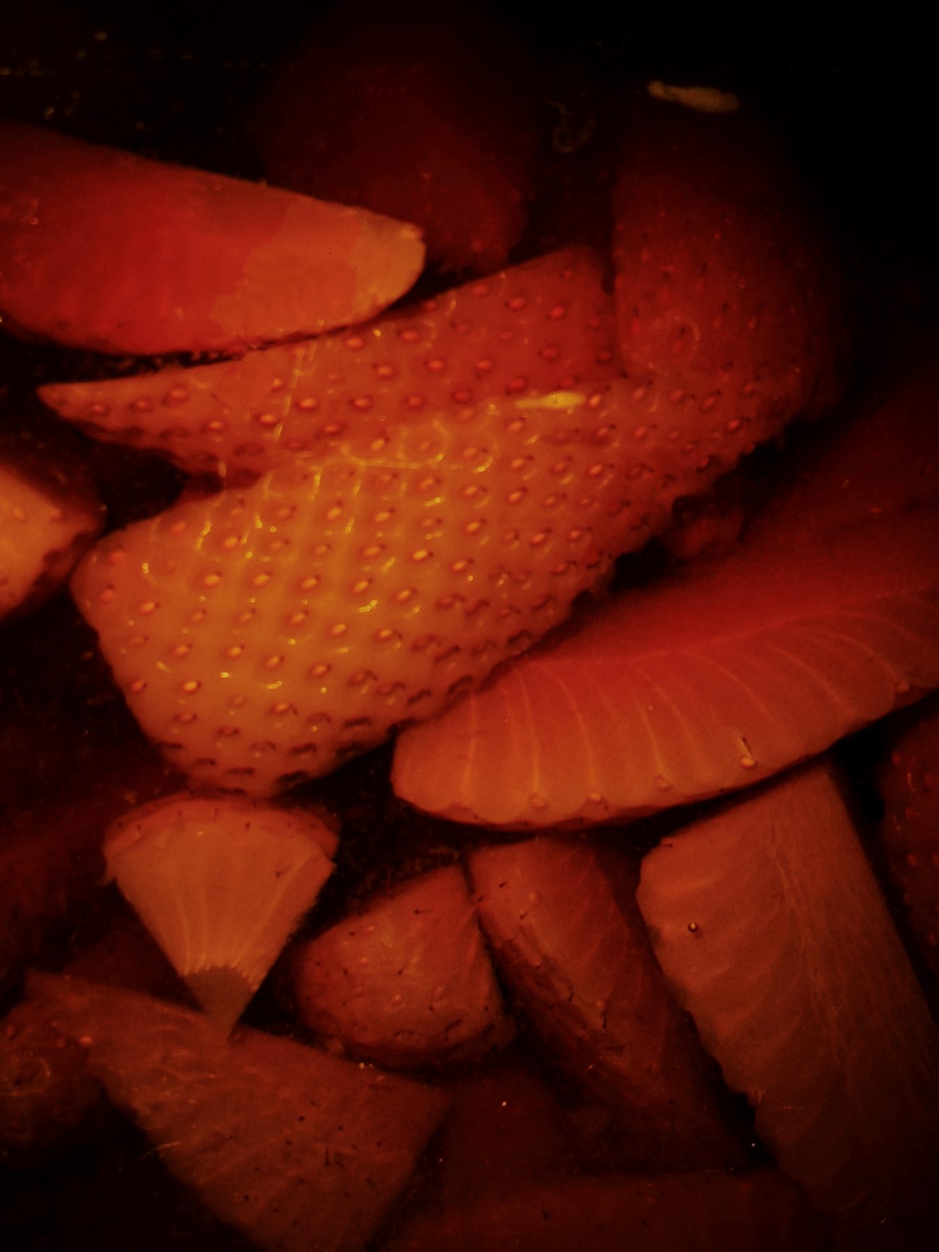 Macro close-up of fresh strawberries submerged in dark infusion at Soluble Solids