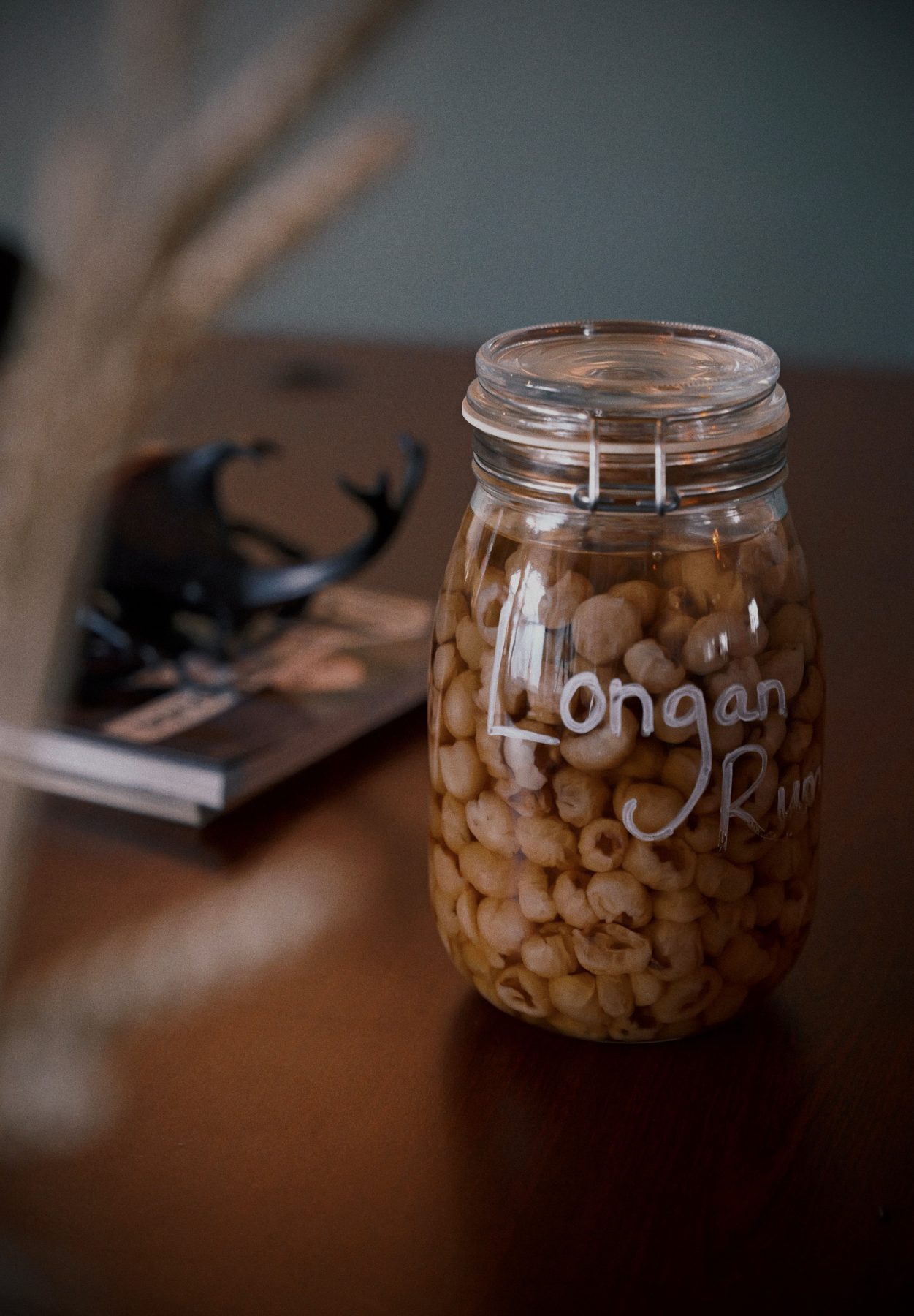 Glass jar labelled 'Longan Rum' filled with infused longan fruit at Soluble Solids
